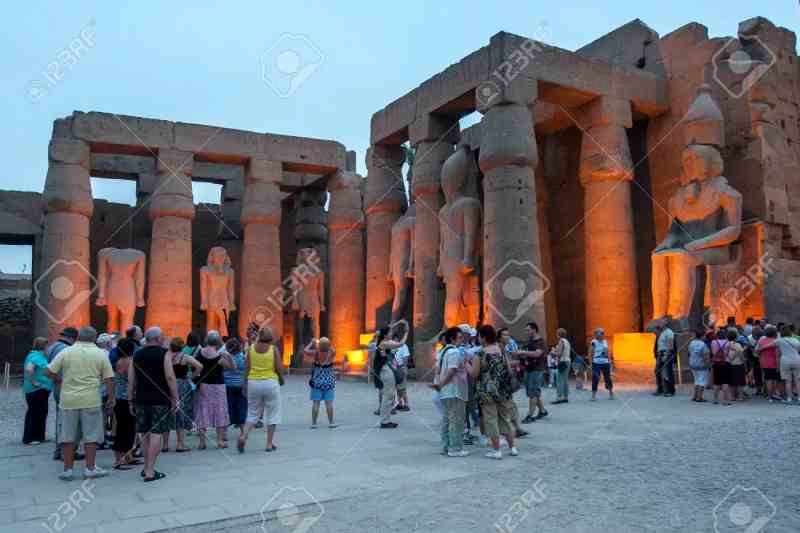Les touristes regardent le soleil se coucher sur le temple de Karnak à Louxor